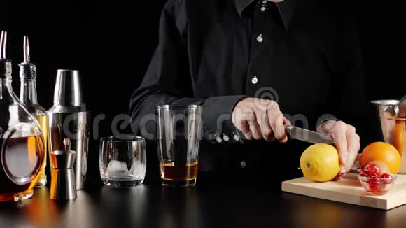 威士忌酸鸡尾酒酒保拿着一把刀把一个黄色多汁的柠檬切成两半放在木板上半滴柠檬视频的预览图