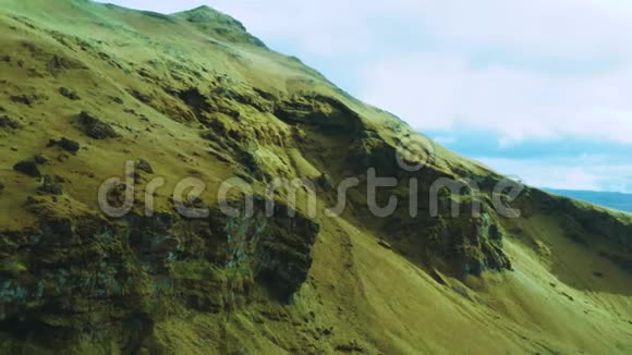在阳光明媚的日子里令人惊叹的鸟瞰与山峰鸟儿在岩石山上飞翔冰岛的无人山景视频的预览图