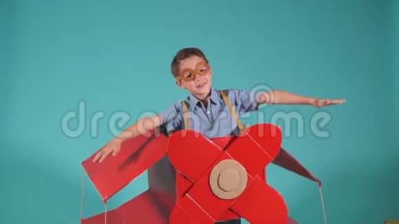快乐的微笑男孩张开双臂在天空中飞行同时在纸板箱上以飞机的形式飞行视频的预览图