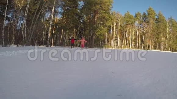 一男一女带着奔跑跳跃的雪脸朝下在冬天森林的背景下天气晴朗走进视频的预览图