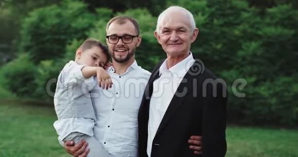 充满魅力和微笑的老人和他的儿子和孙子在公园中央的镜头前享受着视频的预览图
