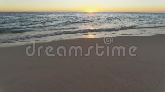 日落于平静的大海潮湿的沙滩在前景视频的预览图