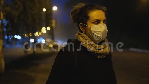 冠状病毒保护一位戴着医用防护面罩的年轻女性站在欧洲的一条城市街道上手里拿着智能手机视频的预览图