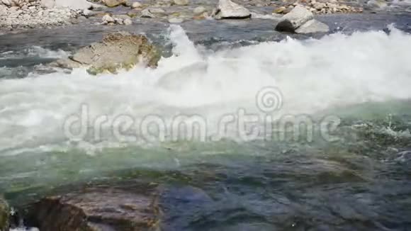 慢动作快速的河流流过锋利的岩石产生白色的波浪喷洒水和泡沫视频的预览图