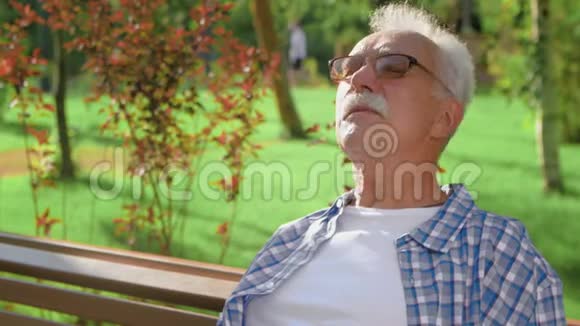 祖父坐在长凳上等着孙子们在公园玩耍视频的预览图