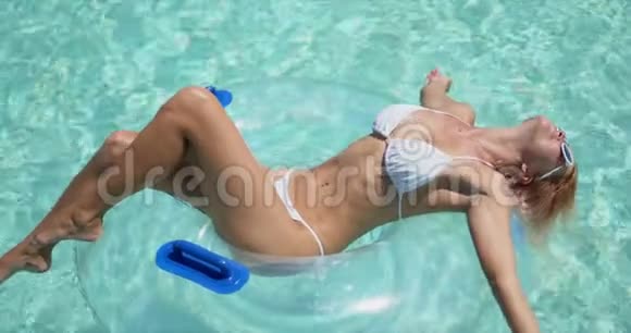 女人在游泳池里放松躺在橡胶圈上视频的预览图