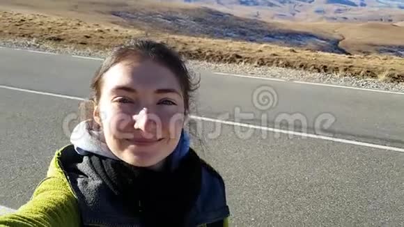 布鲁内特女孩旅行者在柏油路的背景下拍摄一张自拍前往俄罗斯视频的预览图