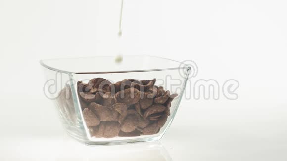新鲜健康食品牛奶倒入透明碗中白色背景上有巧克力麦片片健康的概念视频的预览图