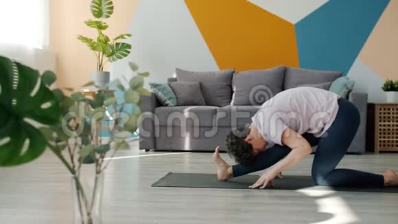 灵活的年轻女子在家里做瑜伽独自在舒适的垫子上练习体式视频的预览图
