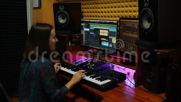女子在电钢琴演奏和创作歌曲在专业录音室女音乐家会弹钢琴键盘和键盘视频的预览图