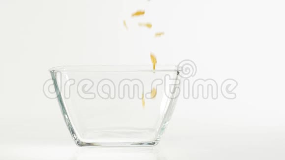 新鲜健康食品黄色的玉米片落在白色背景的透明方形碗里健康早餐的概念视频的预览图
