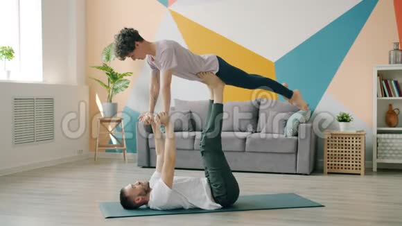 快乐的一对夫妇一起练习瑜伽一起做公寓里的助阵视频的预览图