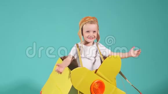 漂亮的小男孩穿着黄色玩具飞机站在蓝色的地方视频的预览图