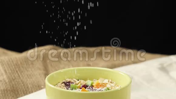 新鲜健康食品白色椰子片落在一个绿色的碗里里面放着燕麦片蜜饯葡萄干和蔓越莓视频的预览图