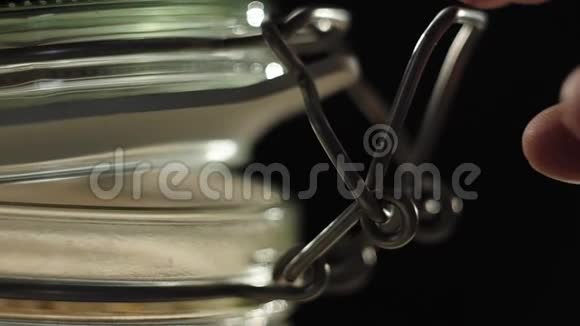 新鲜健康食品手关上一个放在木桌上的燕麦麦片的罐子把燕麦麦片倒进玻璃旁边的绿色碗里视频的预览图
