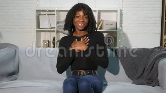 头发卷曲的漂亮黑人女士坐在灰色沙发上说话视频的预览图