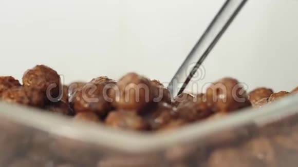 新鲜健康食品勺子从白色背景的透明碗里拿着牛奶的巧克力麦片球概念视频的预览图