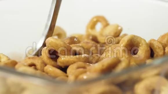 新鲜健康食品勺子从白色背景的透明碗中用巧克力牛奶抓取黄色谷物视频的预览图