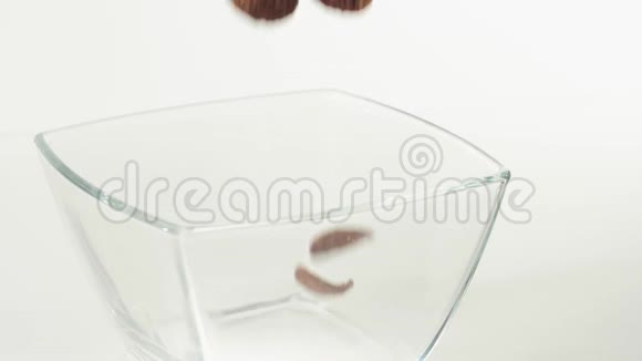 新鲜健康食品巧克力麦片片落在白色背景的透明方碗里健康的概念视频的预览图