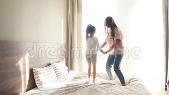 欢乐嬉戏的女孩在床上跳跃玩得开心牵手快乐在一起充满爱的气氛视频的预览图