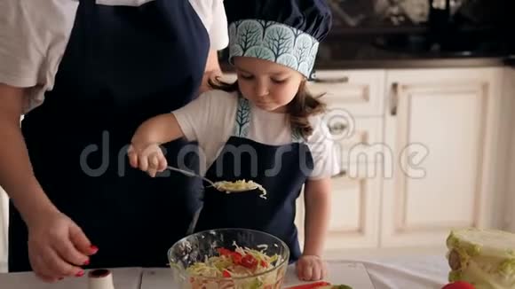一个三岁小女孩用勺子吃蔬菜沙拉的特写镜头视频的预览图