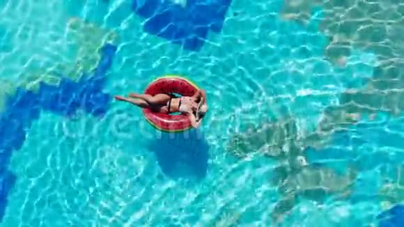 一位女士躺在游泳池里的游泳圈上暑假期间无忧无虑的女士视频的预览图