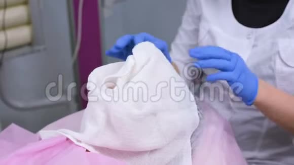 美容师从女人脸上取出毛巾美容师从女人的保湿面膜上取出一层塑料膜视频的预览图