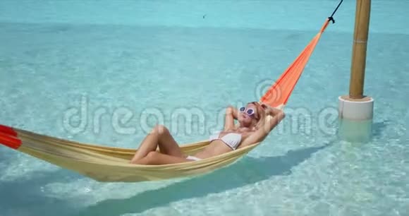 放松的女人躺在游泳池的吊床上视频的预览图