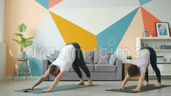 女人和男人在家工作同时在垫子上做瑜伽视频的预览图
