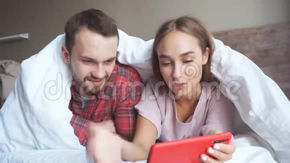 快乐的情侣拿着红色的小玩意用手机看有趣的视频视频的预览图
