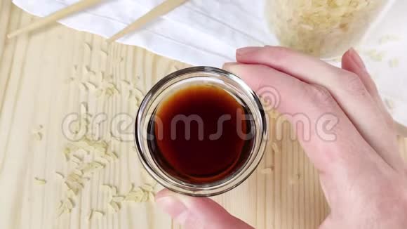 透明玻璃肉汁船中的酱油女性手握并展示圆形碗亚洲菜肴的传统配料木制视频的预览图