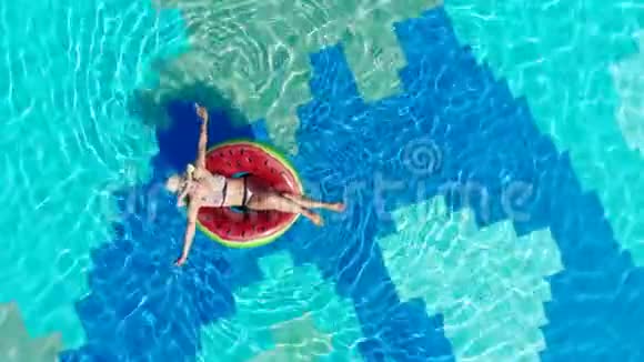 女人在一个大游泳池里放松漂浮在戒指上视频的预览图
