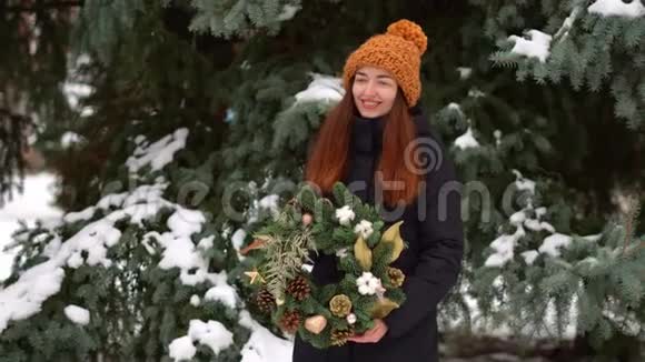白雪皑皑的白天美丽的白种人女孩和户外圣诞花环视频的预览图