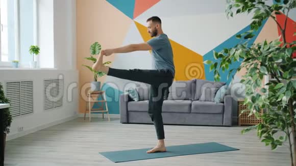 男性成人练习平衡体式单腿站立在垫子上做瑜伽视频的预览图