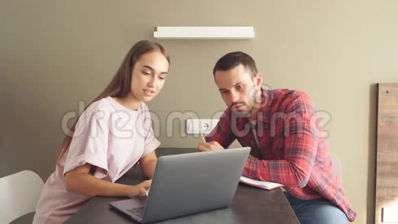 可爱的年轻夫妇在明亮的卧室里讨论日常工作使用笔记本电脑视频的预览图