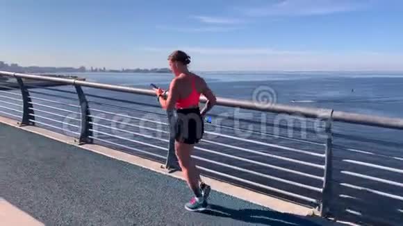 一个年轻女孩带着一瓶水和一部智能手机跑步视频的预览图