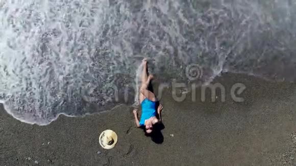 一个女人喜欢度假躺在海滩上的水里暑假概念视频的预览图