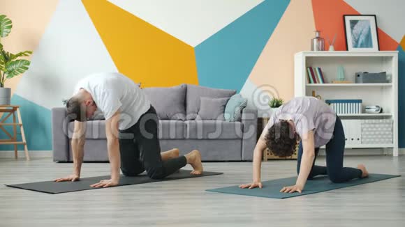 夫妻双方在公寓里一起做瑜伽运动缓慢同时照顾健康视频的预览图