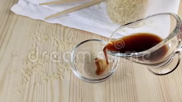 透明玻璃肉汁船中的酱油亚洲菜肴的传统配料木制桌子特写散落的谷物视频的预览图