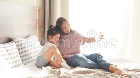 两个漂亮的女孩在卧室里玩得很开心漂亮的女人用手机拍照视频的预览图