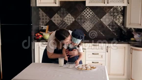 一个年轻快乐的母亲吻她的女儿他们一起做饼干视频的预览图