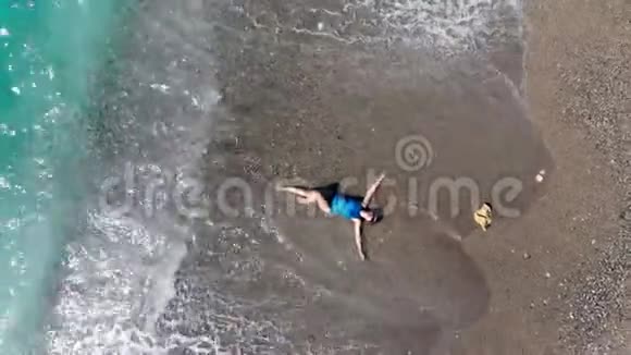 一个女孩躺在水中的海滩上海浪拍打着海岸暑假概念视频的预览图