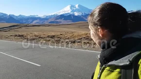 女孩旅行者在埃尔布鲁斯旅行时自拍在一条美丽的道路的背景下在高加索山脉的埃尔布鲁斯山视频的预览图