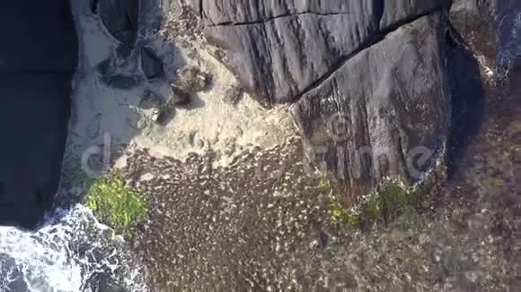 黑色的女士躺在大海环绕的巨大岩石悬崖上视频的预览图