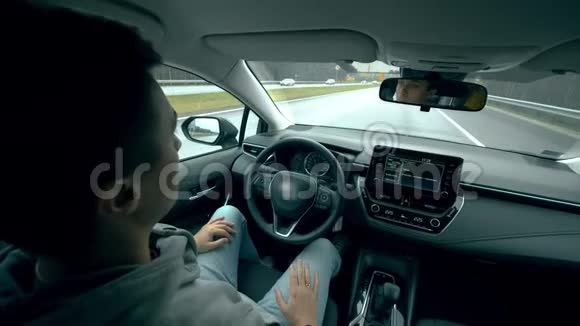 年轻人坐在车里自驾着车自动驾驶汽车智能车辆无驾驶汽车概念视频的预览图