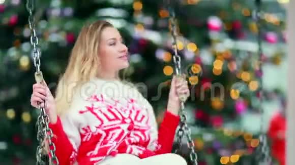 穿着红色圣诞毛衣的女孩在秋千上视频的预览图
