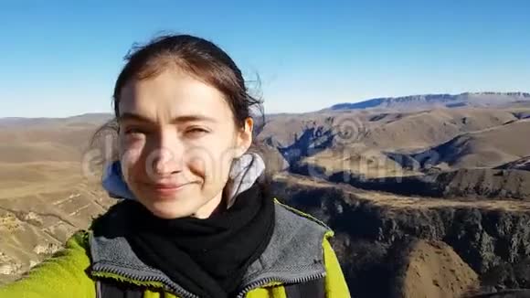 女孩旅行者在美丽的沙漠岩石峡谷的背景下自拍享受阳光的灿烂眯着眼睛视频的预览图