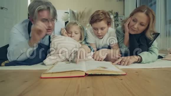 孩子们正在地板上和祖父母一起读一本书视频的预览图