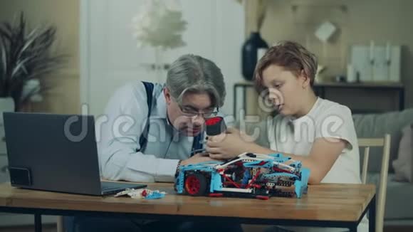 爷爷和一个十几岁的男孩正在建造一辆玩具车视频的预览图
