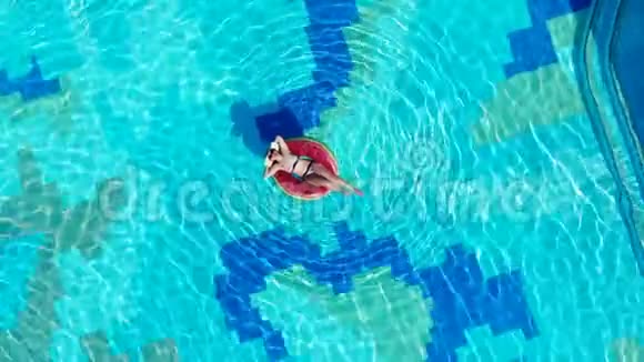 一个游客躺在游泳池里躺在漂浮的环上视频的预览图